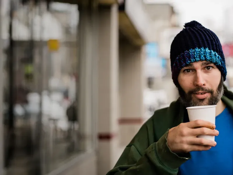 Man walking outside with hot coffee.