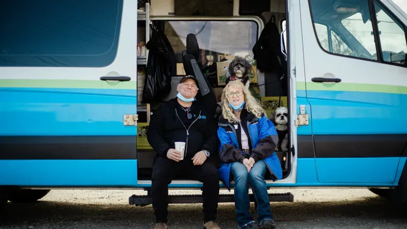 Ed, Shelley and 2 puppies sitting in a UGM Mobile Mission rescue van