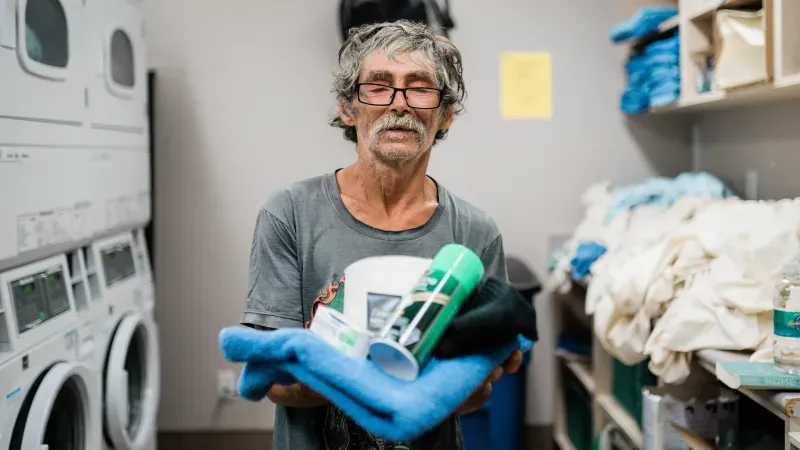 a shelter visitor holding towel and other necessities