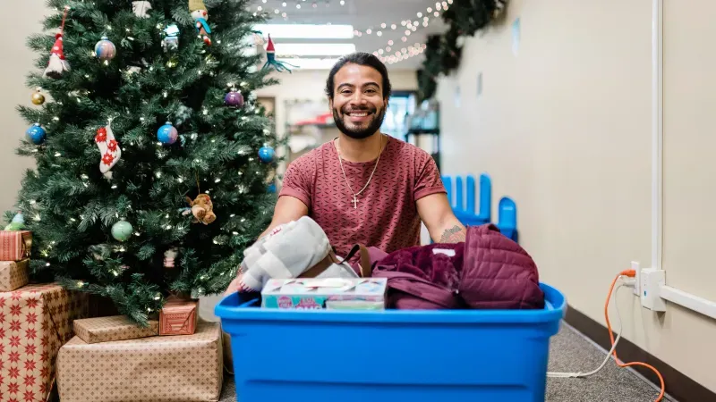 Outreach Worker Joshua filling a Christmas Hamper with winter clothes, household necessities, and toys