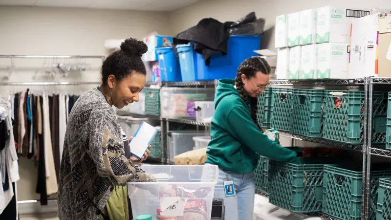 UGM staff filling a food hamper with items from supply room. 